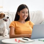 joyful-asian-lady-surfing-on-internet-cute-puppy-2022-12-16-08-55-57-utc