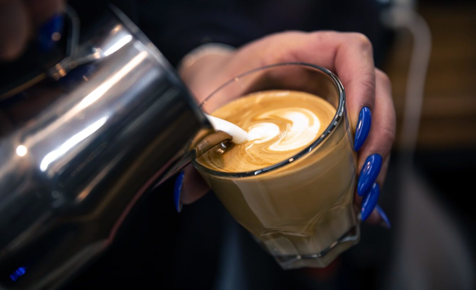 close-up-hand-of-a-woman-barista-pouring-froth-milk-in-espresso-coffee-1-1-e1651656060473-1536x937