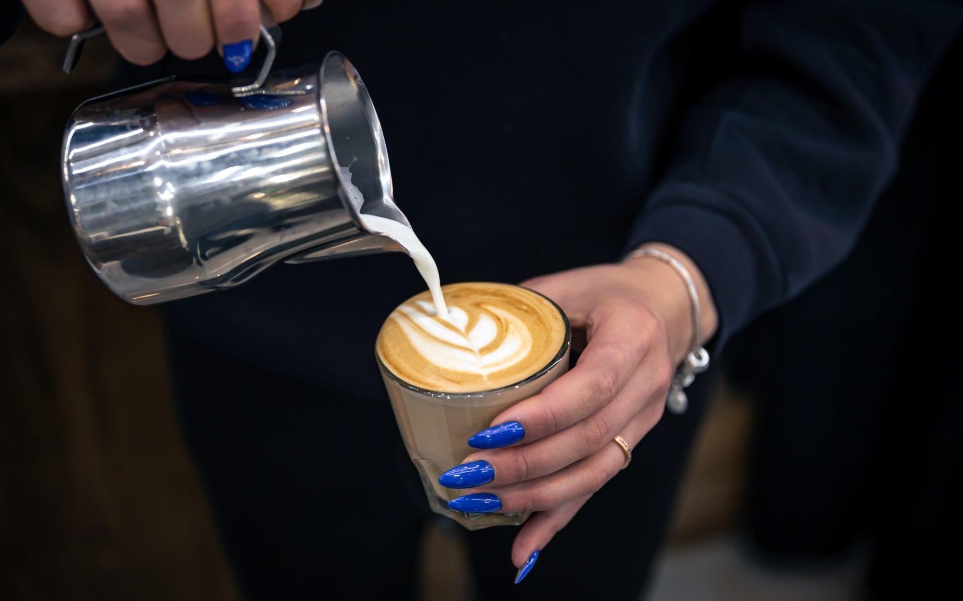 close-up-hand-of-a-woman-barista-pouring-froth-milk-in-espresso-coffee-e1651630473618